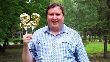 大个子拿着金色的气球，把23号放在户外。 23周年庆祝晚会